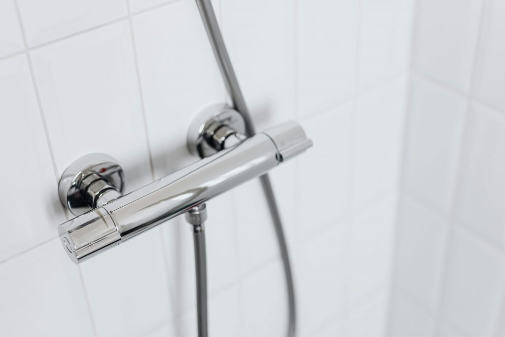 Modern chrome shower faucet on white tiled wall, elegant and clean design.